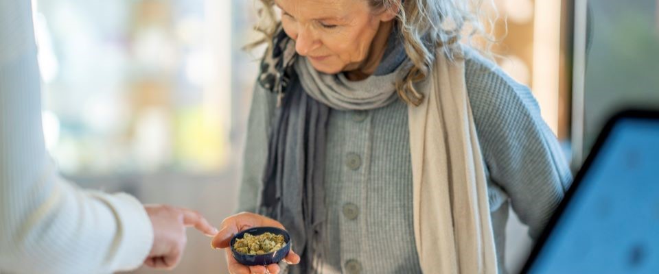 professional person points to sample of cannabis in the a container in the hand of a client